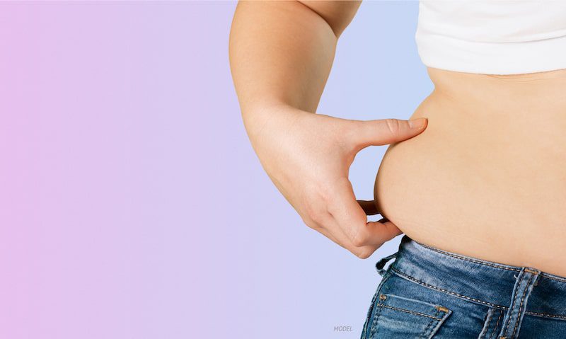 Woman pinching oblique fat over her jeans.