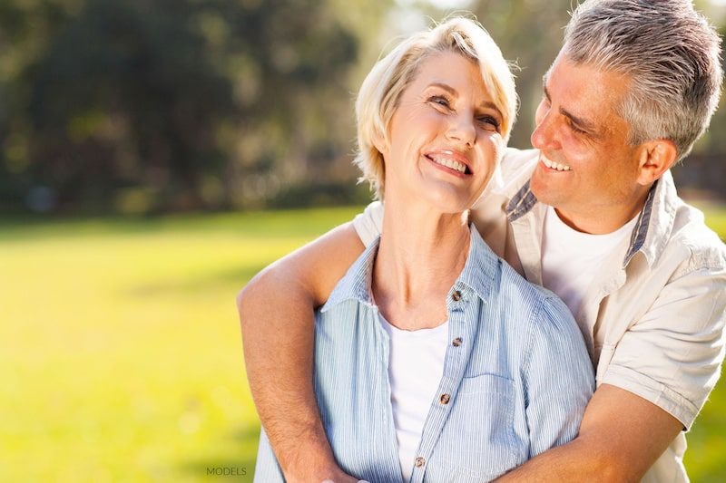 Attractive middle-aged couple holding and smiling at each other in the park