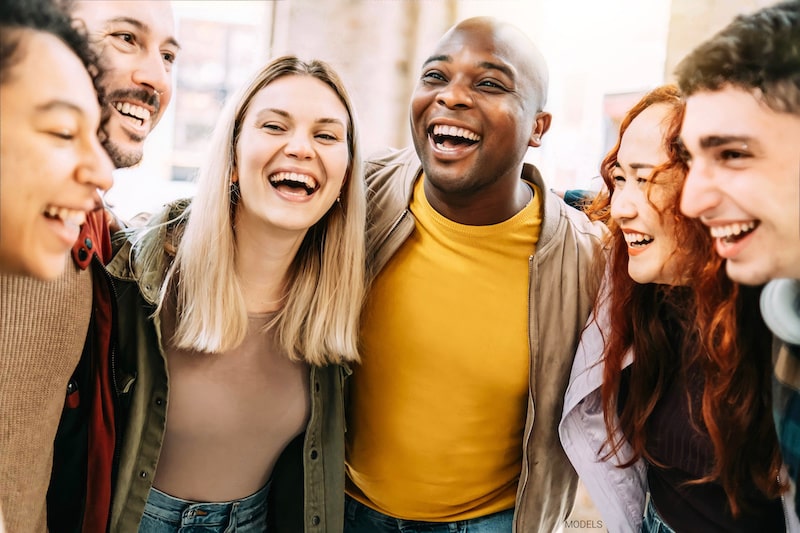 Group of attractive millennial friends gathered together and smiling at each other