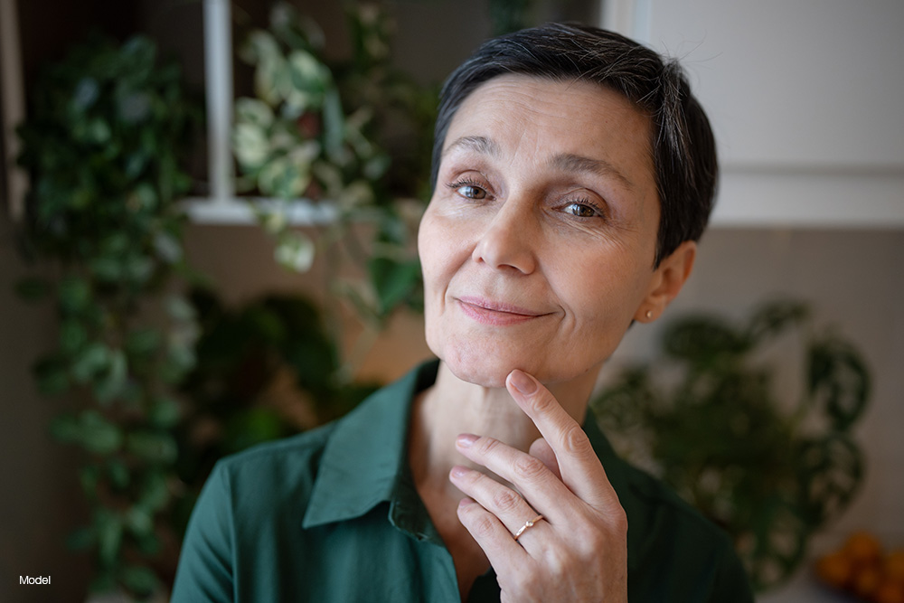 Mature woman in green shirt touching her chin